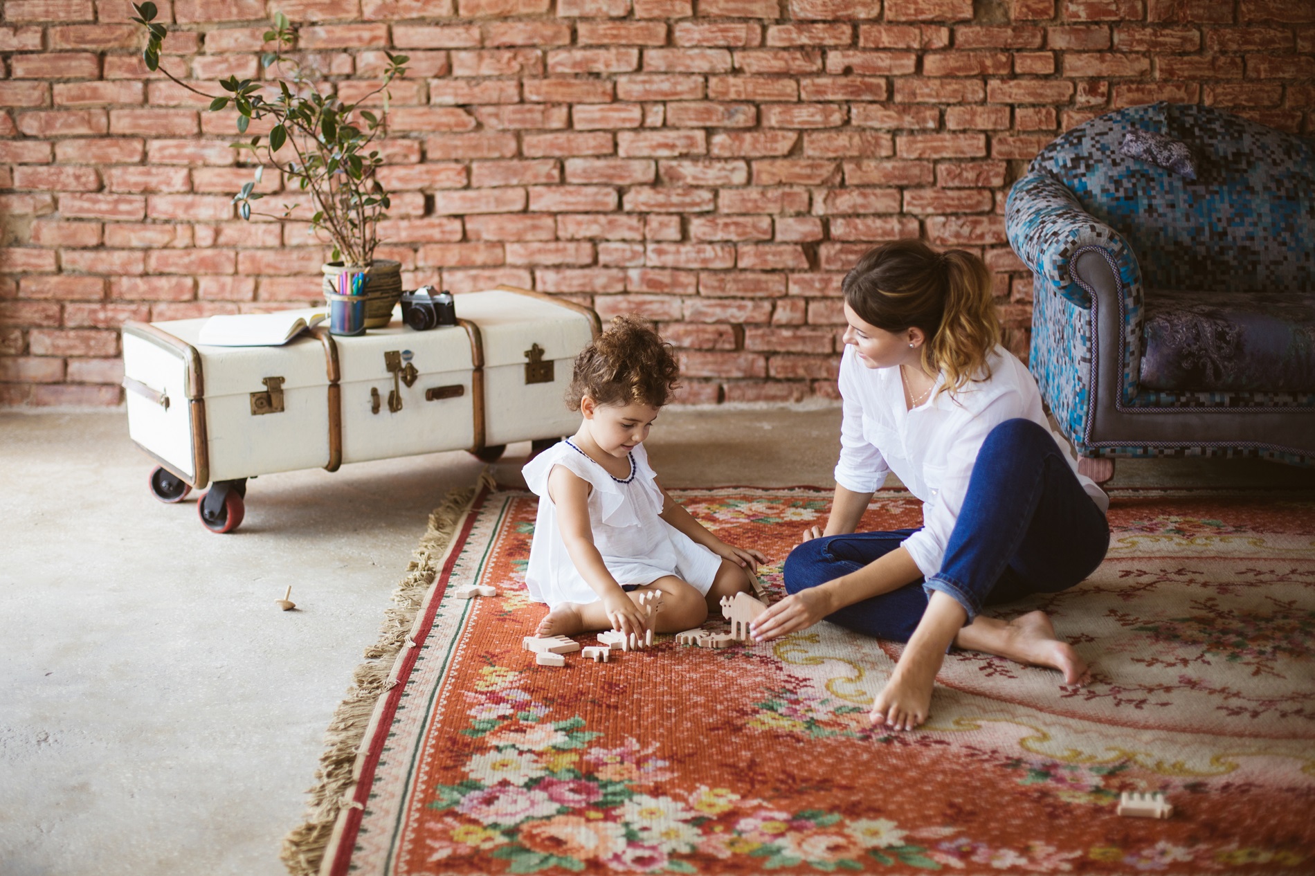 A woman and her daughter are sitting in front of a washing machine.