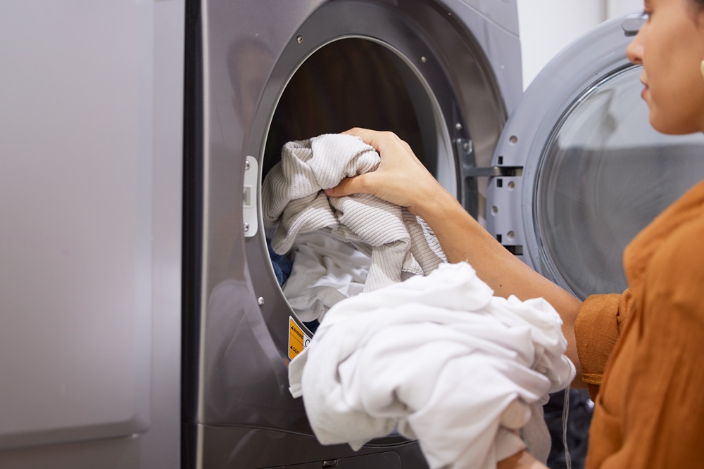 Person loading or unloading clothes into a front-loading washing machine.