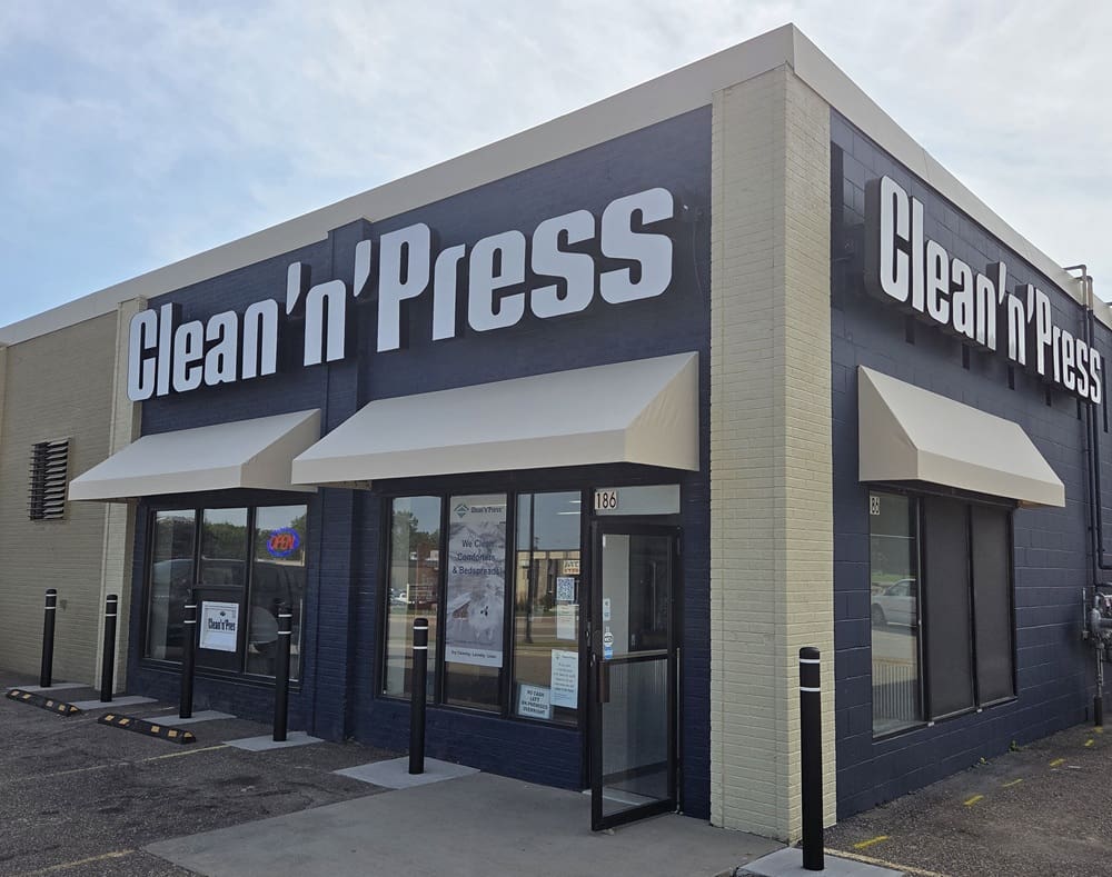 A dry cleaning store named Clean'n'Press, with a sign promoting comforter and bedsheet cleaning services in its window.